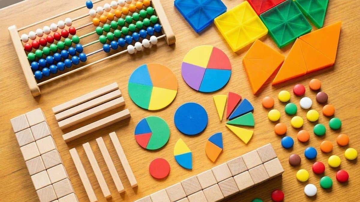 Assorted math manipulatives including base ten blocks, fraction tiles, and pattern blocks on a wooden table