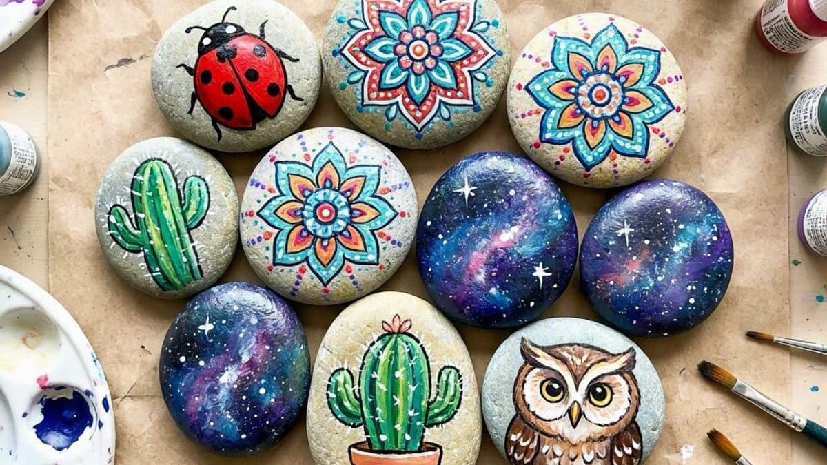 Collection of colorful painted rocks with animals and patterns drying on newspaper